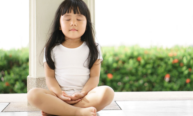 child practicing calming breathing and meditation