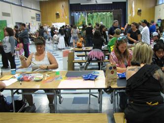 people in cafeteria, doing arts and crafts at table.